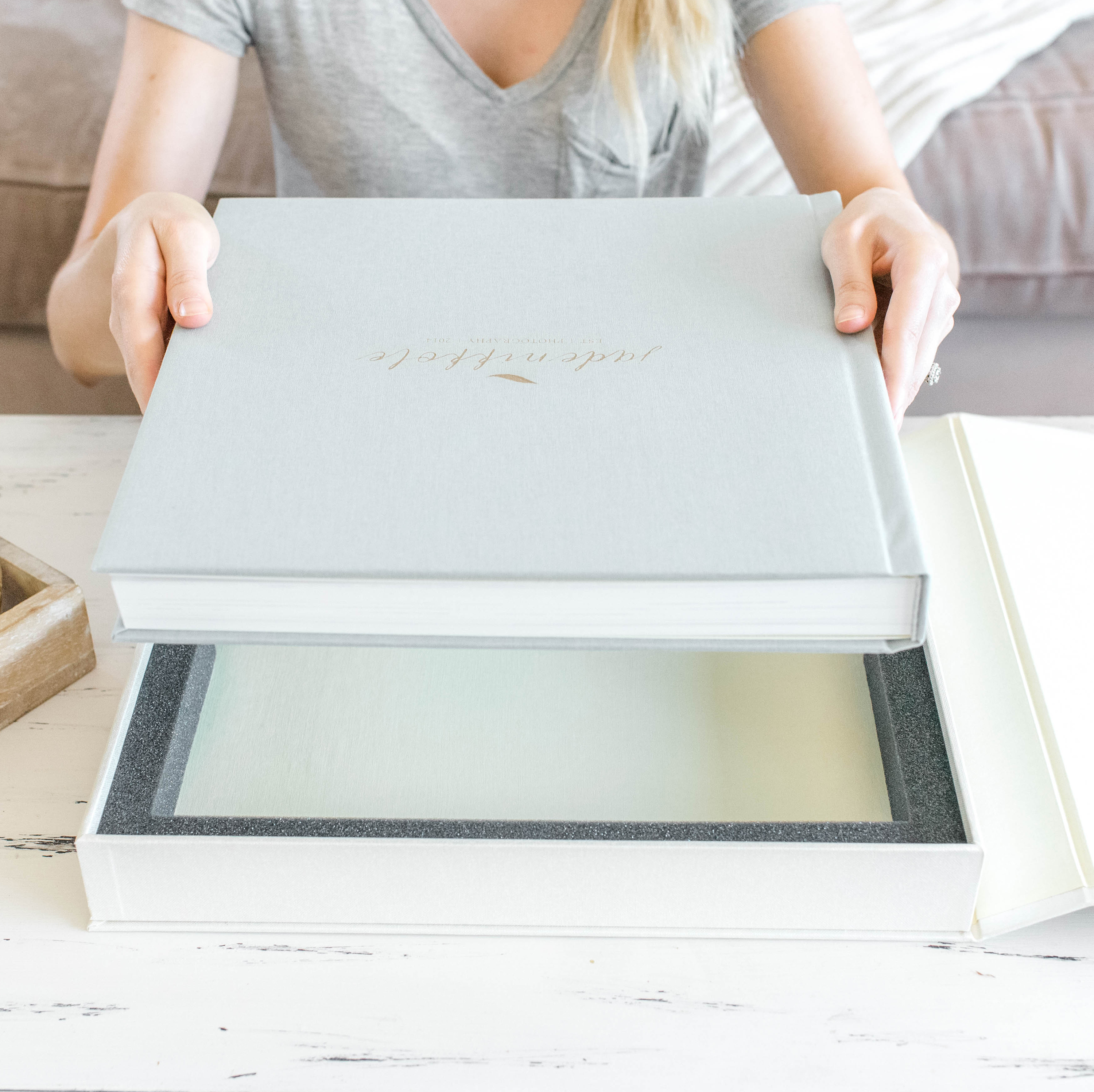 Women taking wedding album out of white presentation box