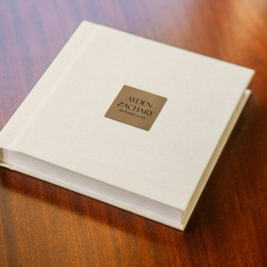 Baby photo album with cream vegan leather cover and engraved metal plate title for Ayden Zachary