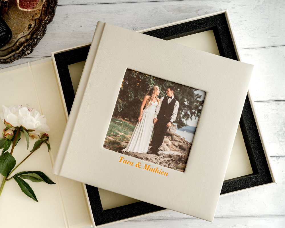 Leather photo book for wedding memories featuring a small square photo window and the names Tara & Mathieu embossed in gold, shown in a protective box.
