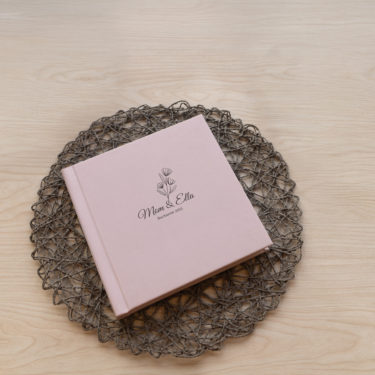 Close-up of a rose linen layflat photo album cover with a minimalist UV-printed title, designed for a fine art mother-daughter portrait session.