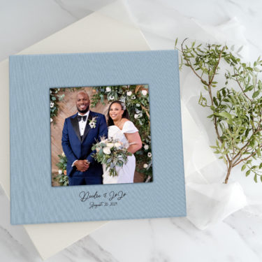 Stone Linen cover of a premium layflat wedding album featuring a front-facing cameo photo and custom UV-printed title for Deidre & JoJo’s wedding