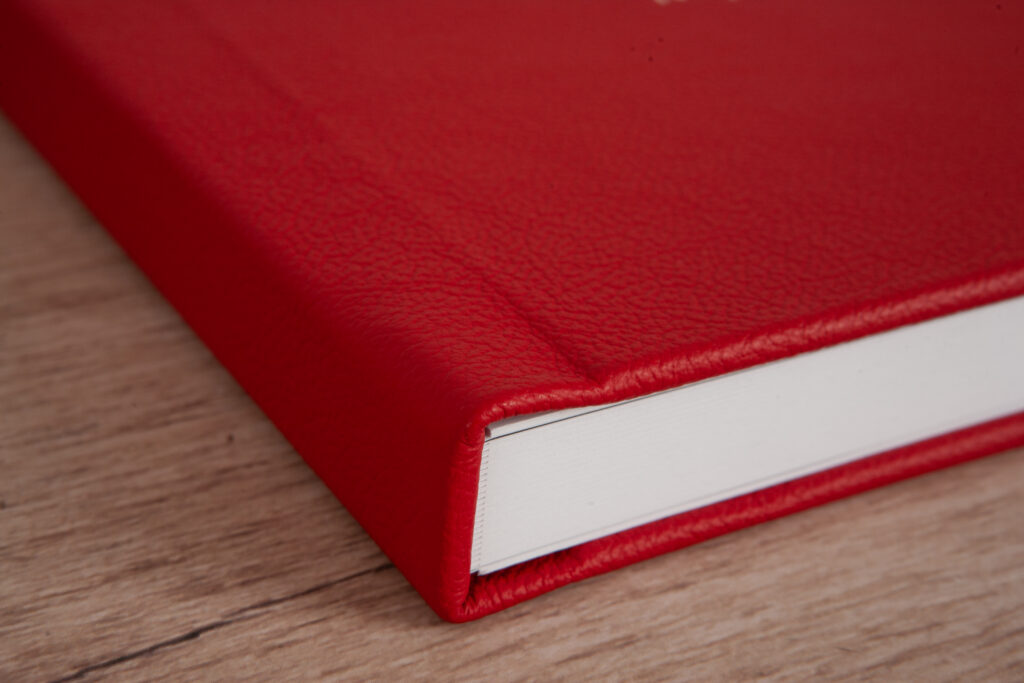 Close-up of the red leather cover on a Premium Layflat family photo album, showing the texture and craftsmanship.