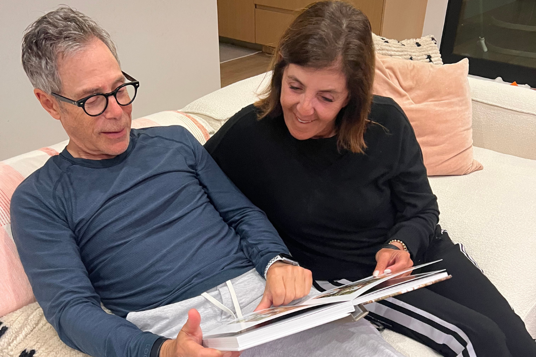 Samara’s parents sitting together, turning the pages of a custom photo book she created for them as a Christmas gift.