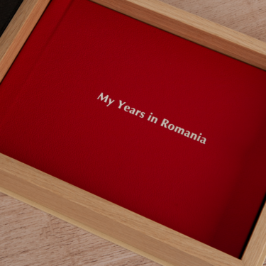 Red leather family photo album titled “My Years in Romania” placed inside a champagne linen presentation box.